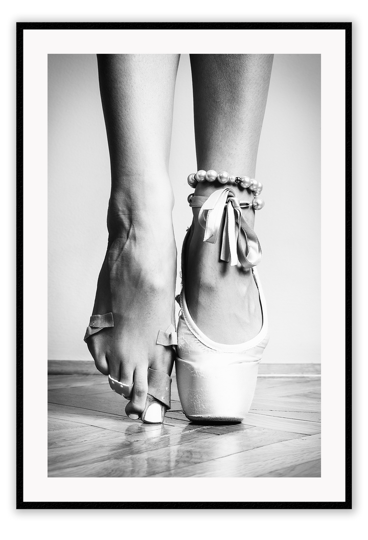 A vintage black and white wall art with a ballerina in point shoes close-up