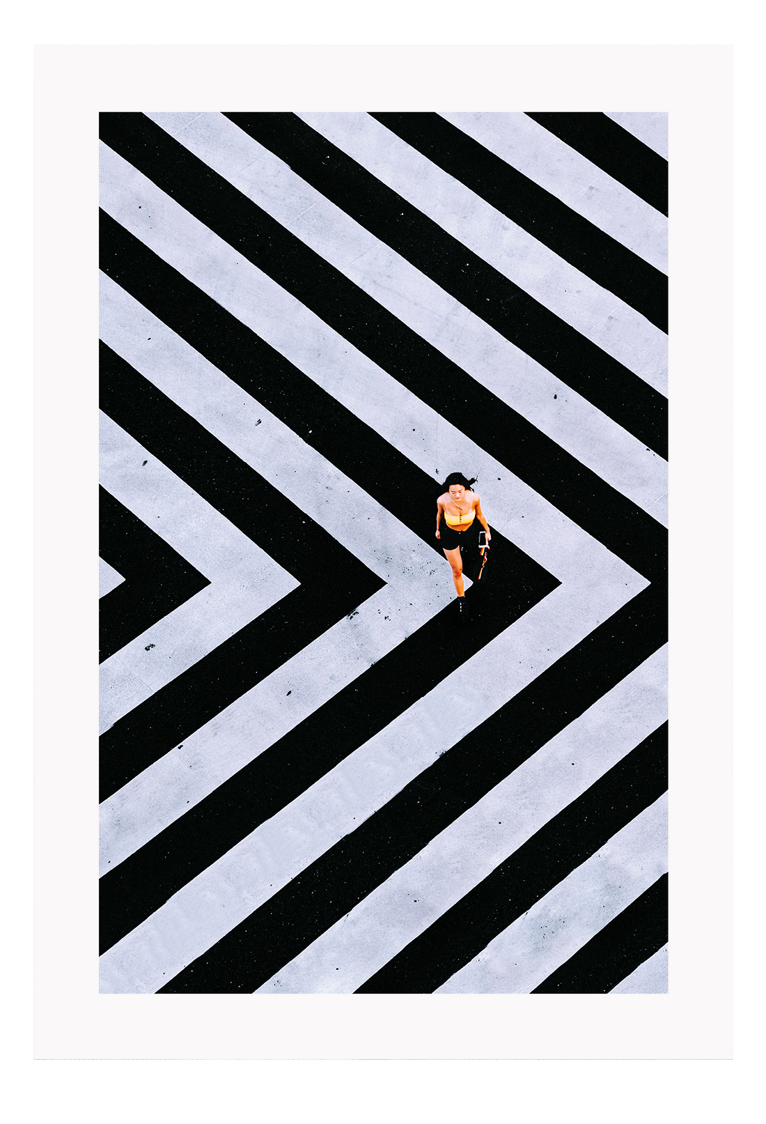 An urban wall art with an aerial view of a lady walking on black and white street crossing stripes