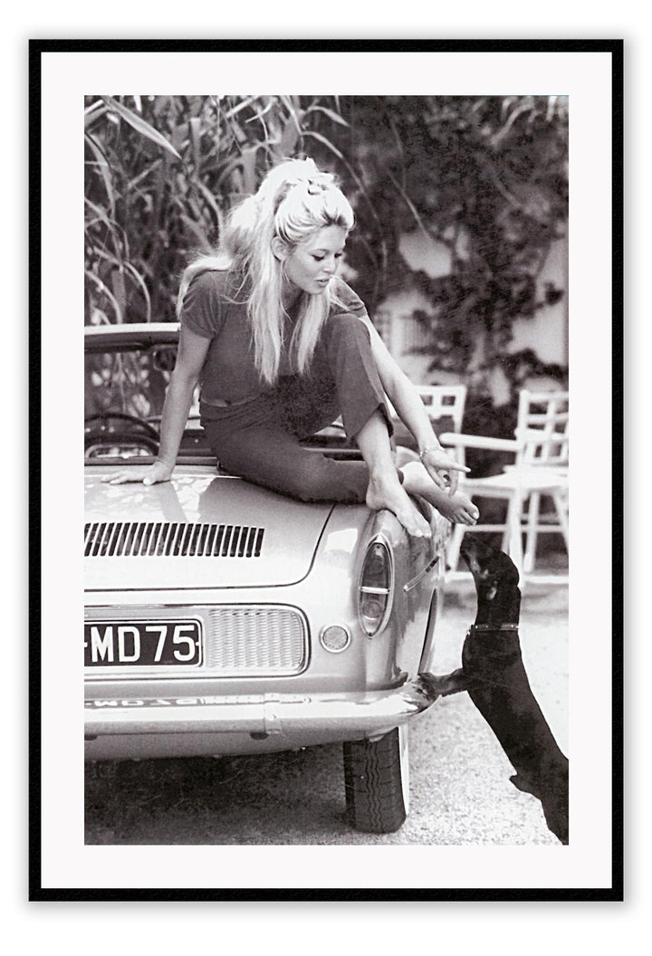 A black and white photo print of a fashion model woman lady on vintage car patting dog dachshund blonde and sexy 