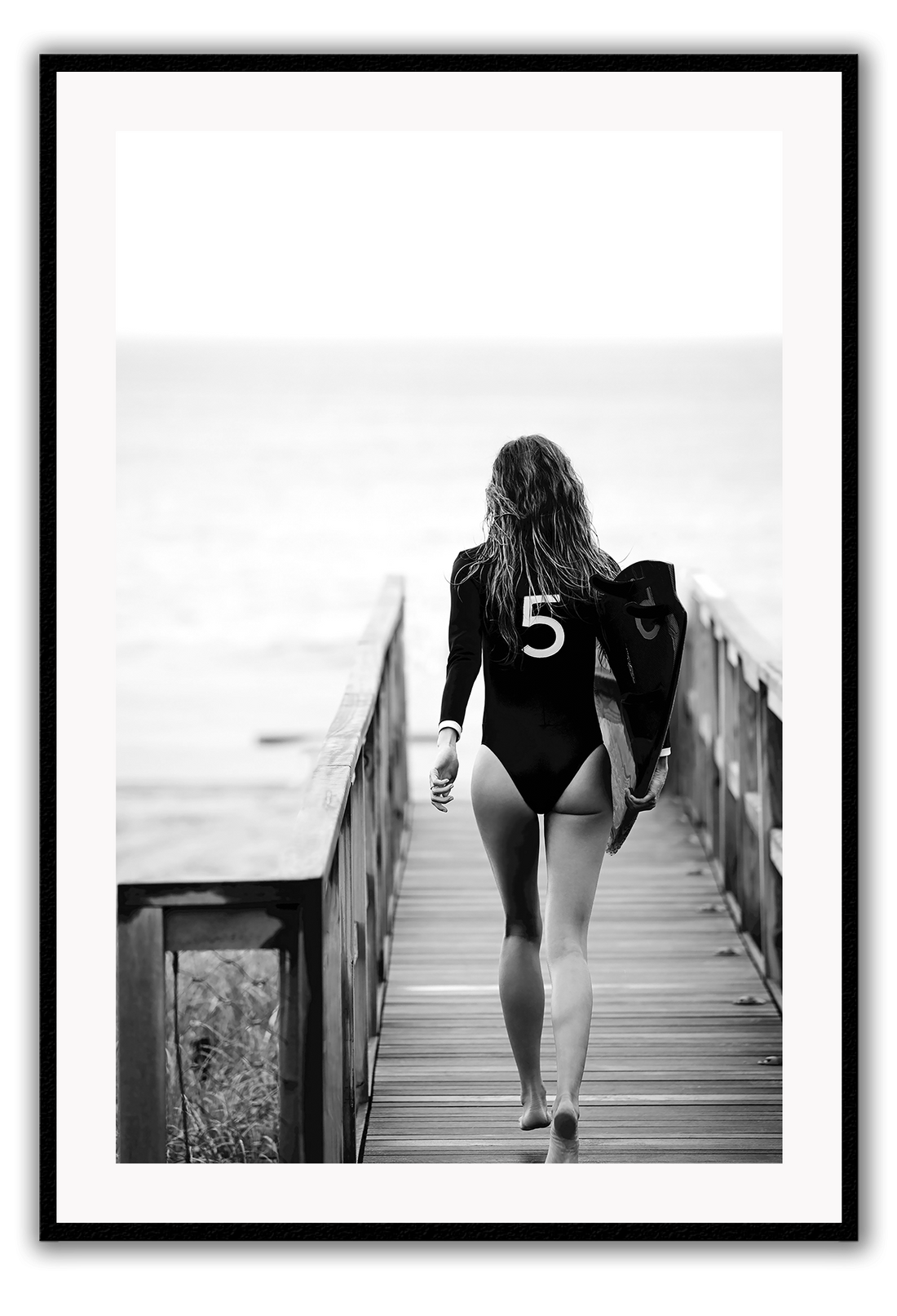 A black and white fashion wall art with fashion model Gisele Bunchen holding Chanel N5 surf board. 